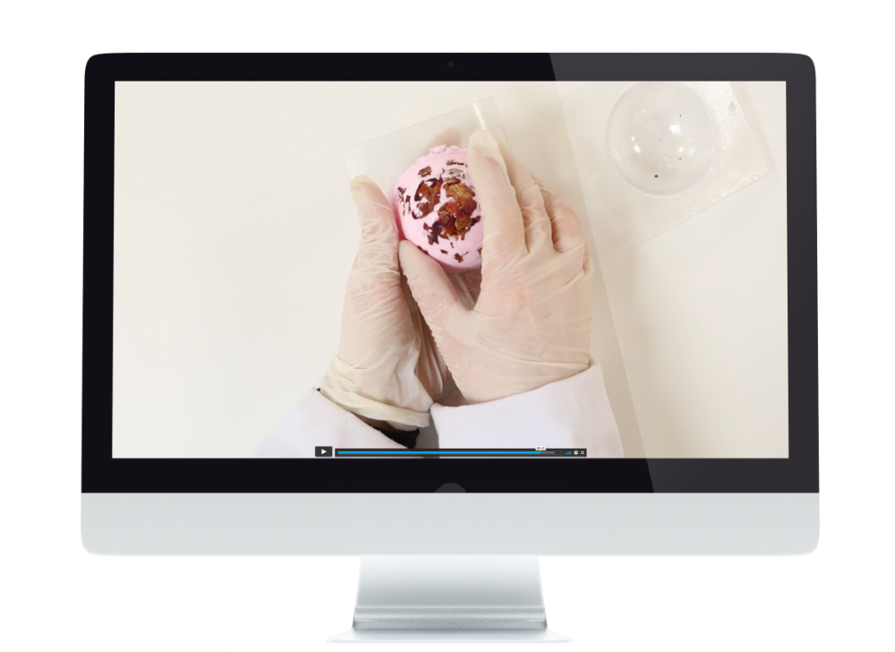 Gloved hands holding a pink soap bar.